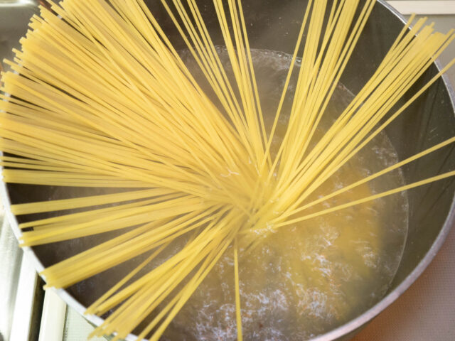 鍋にお湯を沸かし、塩を適量溶かしてからパスタを加えた写真