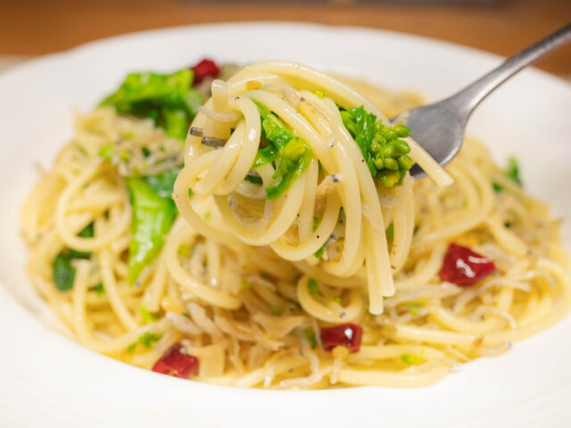 パスタと菜の花をフォークで持ち上げた写真