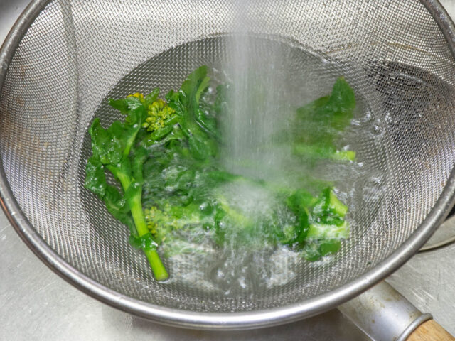 ゆでた菜の花を流水で冷やす写真