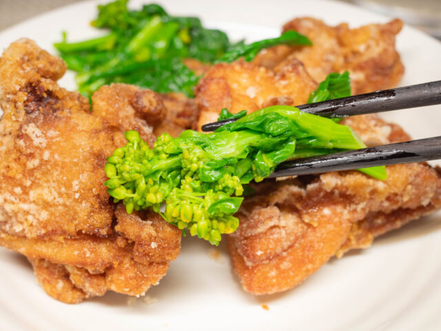 菜の花を箸で持ち上げた写真