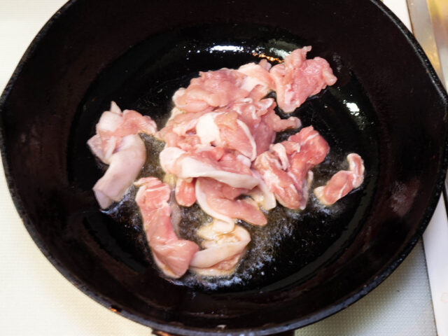 鍋にごま油を熱して豚肉を入れた写真