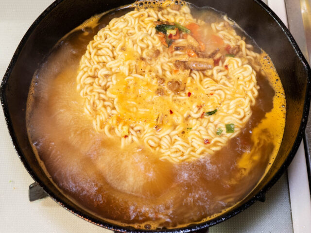 鍋にインスタント麺とかやくを入れた写真