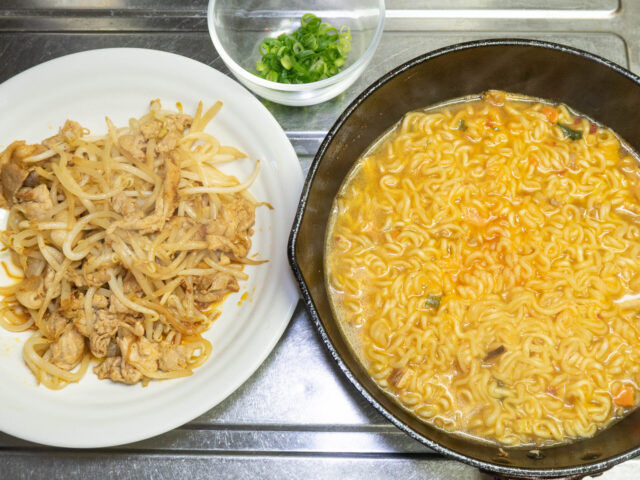 鍋のラーメンと皿の炒めものの写真