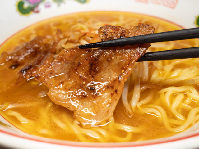 ピリ辛豚バラ肉を箸で持ち上げた写真