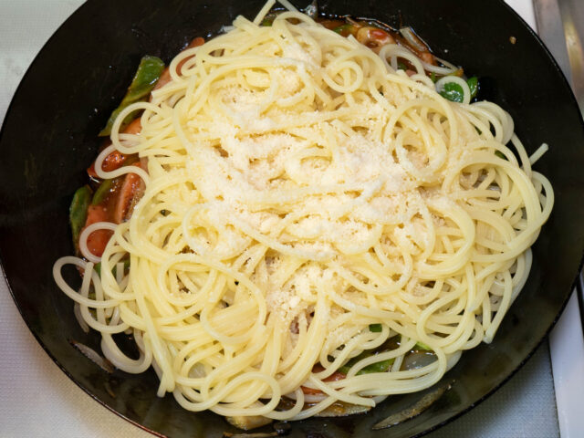 ソースのフライパンに茹で上がったパスタと粉チーズを加えた写真