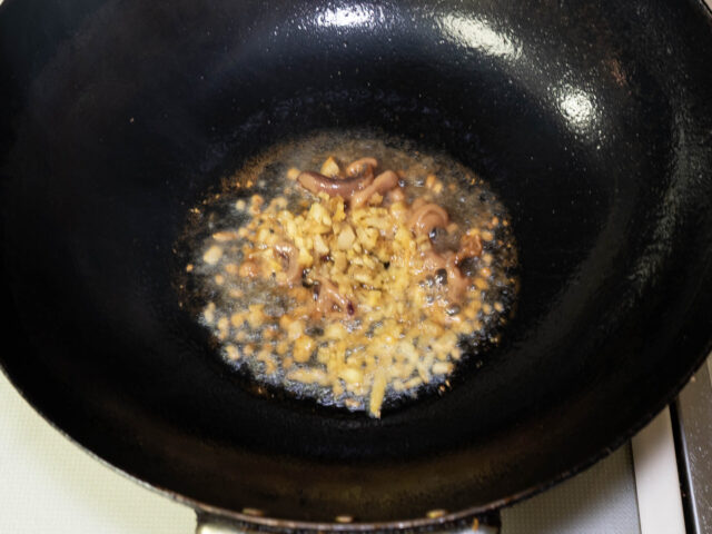 中華鍋にサラダ油を熱して、生姜と塩辛を加えた写真