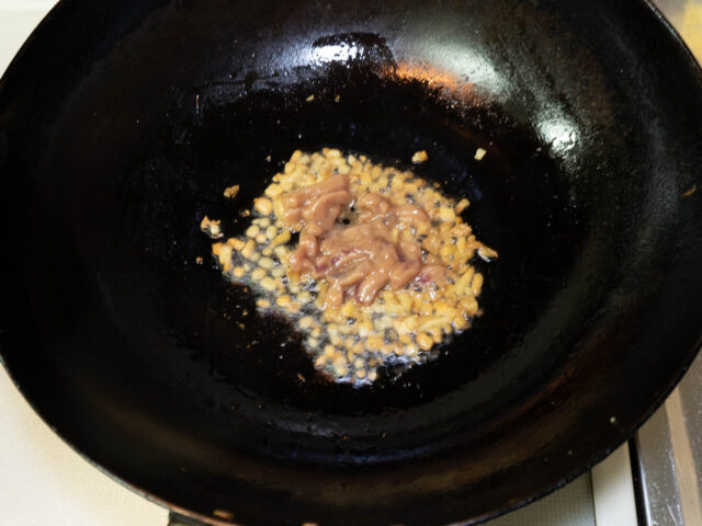 中華鍋にサラダ油を熱して、生姜と塩辛を加えた写真