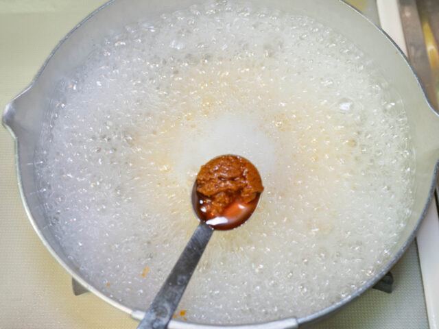 鍋にお湯を沸かし、トムヤムクンペーストを加えようとする写真