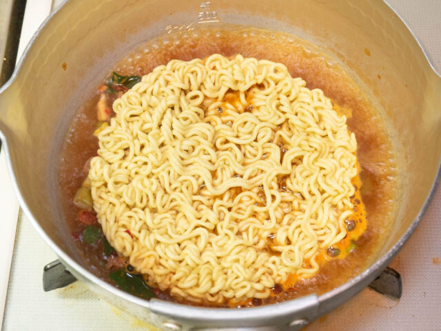 鍋にお湯を沸かし、かやくとスープ、麺を加えた写真