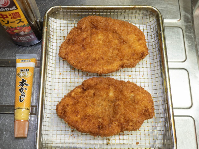 揚げたカツの油を切る写真