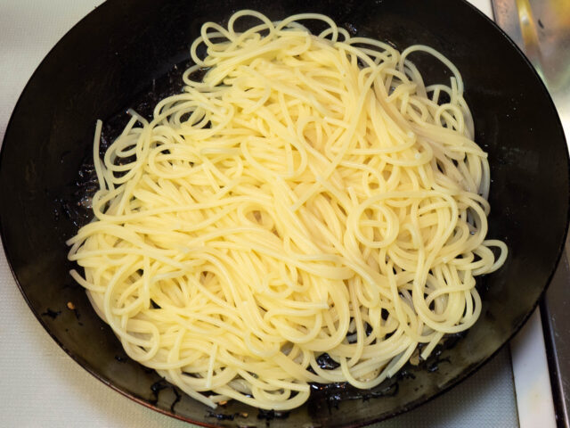 ソースのフライパンに茹で上がったパスタを加えた写真