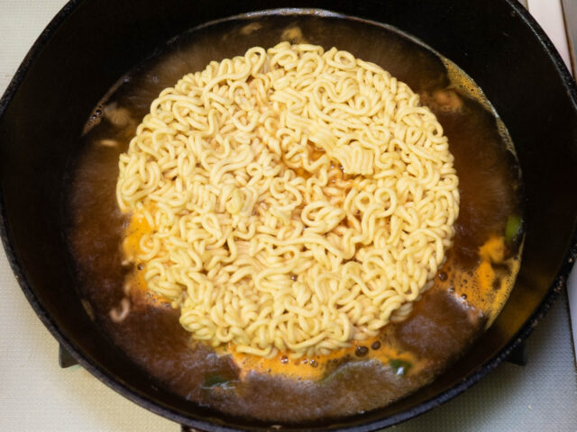 鍋にお湯を沸かし、スープとかやく、インスタント麺を加えた写真