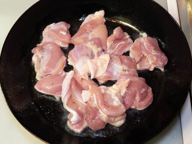 フライパンにサラダ油を熱して、鶏肉を入れた写真