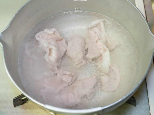 鍋にお湯を沸かし、豚肉を茹でる写真